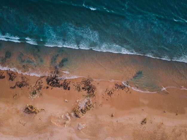 Luchtfoto van de golven van de zee en de zandige kust