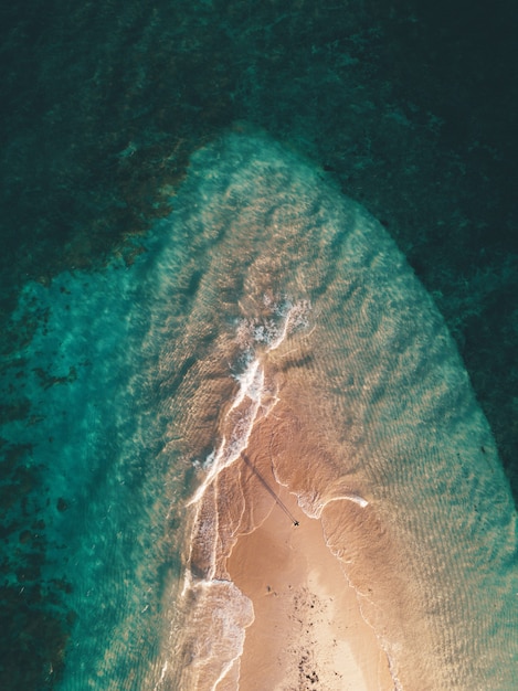 Luchtfoto van de oceaangolven die het kleine zanderige eiland raken