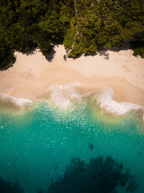 Luchtfoto van de oceaangolven die het zandstrand raken