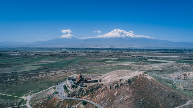 Luchtfoto van een Armeense kerk op een heuvel met berg Ararat en heldere blauwe hemel