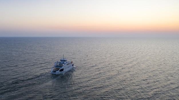 Luchtfoto van een jacht dat vaart in een blauwe zee tijdens de zonsondergang