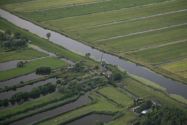 Luchtfoto van een waterstroom midden tussen grasvelden bij Nederlandse polder