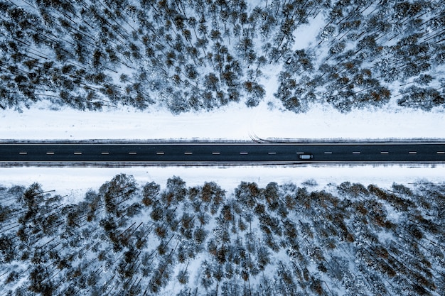 Luchtfoto van een weg in een bos bedekt met de sneeuw tijdens de winter