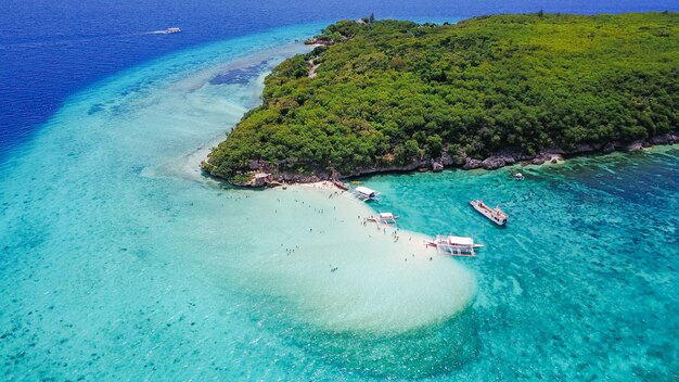 Luchtfoto van het zandstrand met toeristen zwemmen in prachtig helder zeewater van het Sumilon eiland strand landend in de buurt Oslob, Cebu, Filipijnen. - Boost up color Processing.