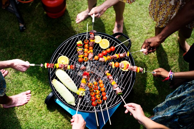 Luchtmening van een diverse groep vrienden die barbecue in openlucht roosteren