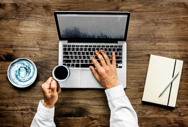 Luchtmening van een mens die computerlaptop op houten lijst met behulp van