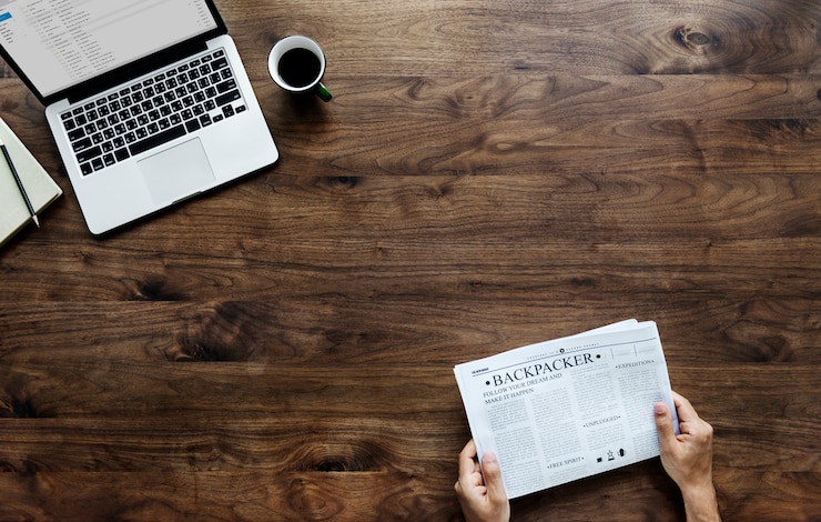 Gratis Foto luchtmening van een vrouw die een krant en computerlaptop op houten lijst lezen