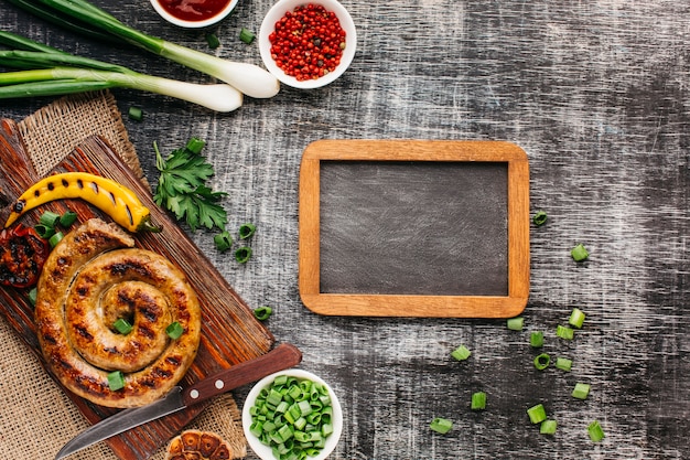 Luchtmening van heerlijke geroosterde worsten en vers ingrediënt met lege lei op houten achtergrond