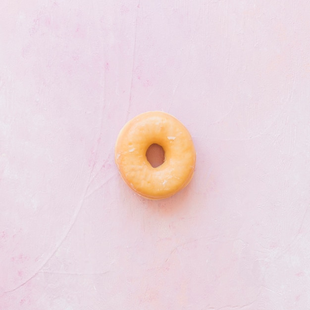Luchtmening van heerlijke verglaasde doughnut op roze achtergrond