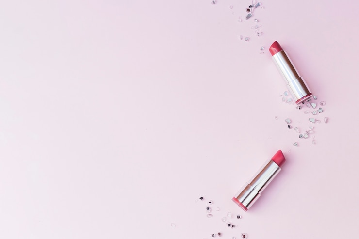 Gratis Foto luchtmening van twee roze lippenstiften en verpletterde glasstukken op roze achtergrond