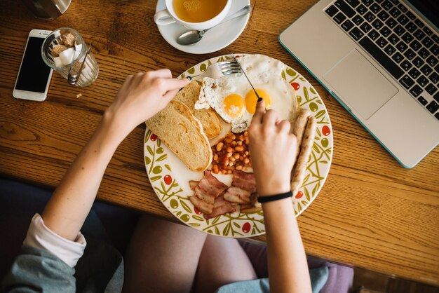 Luchtmening van vrouw die gezond ontbijt in caf��� eten