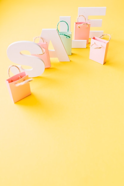 Gratis foto luchtmening van wit verkoopwoord met kleine roze het winkelen zakken op gele achtergrond
