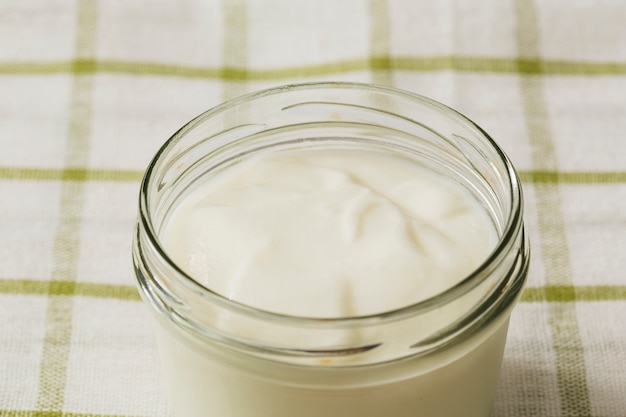 Luchtmening van yoghurt in de open glaskruik op servet