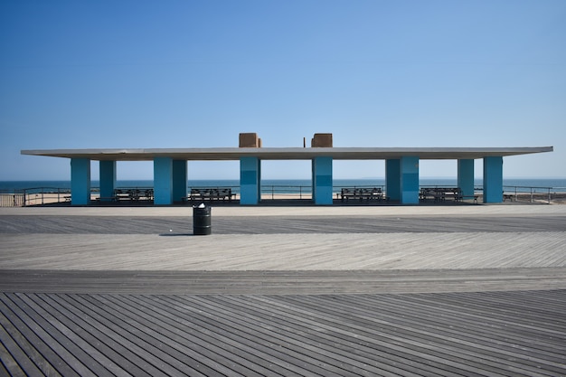 Luifelbouw op het strand met blauwe zuilen, wit dak en banken