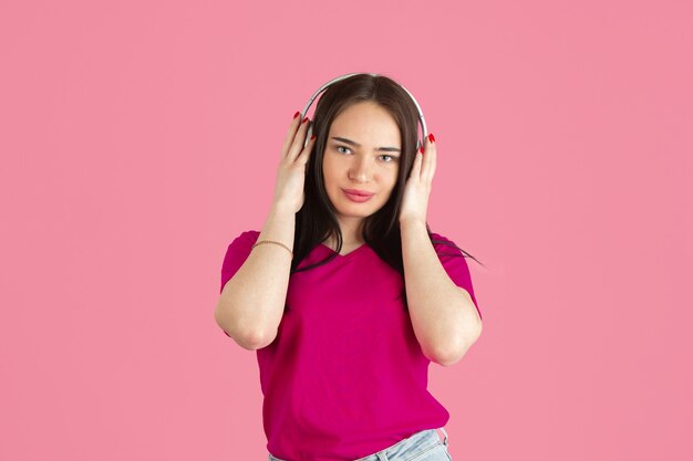 Luister naar muziek. Zwart-wit portret van jonge blanke brunette vrouw geïsoleerd op roze studio muur.