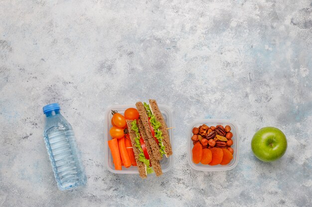 Lunchbox met sandwich, groenten, fruit op wit.