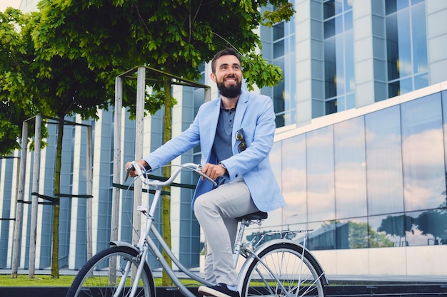 Luxe bebaarde man in een zonnebril op een fiets in het centrum.