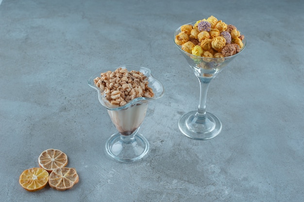 Maïsballen in een glas en cornflakes in een melkkoffieglas, op de blauwe achtergrond.