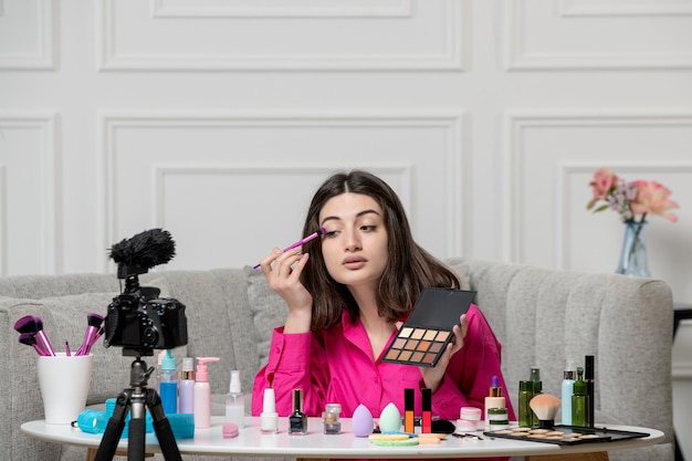 Make-up blogger brunette mooie schattige jonge dame die blog opneemt op camera die schaduwen opdoet