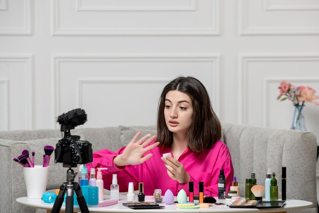 Make-up blogger schattige mooie mooie jonge vrouw die video op camera opneemt met witte crème