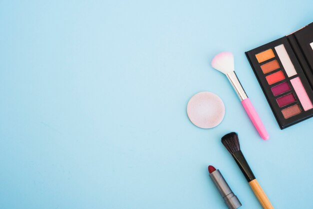 Make-up oogschaduw paletpenseel; spons; lippenstift op blauwe achtergrond
