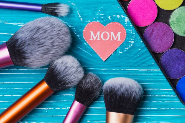 Make-up penselen, gekleurde poeders en document hart voor moederdag