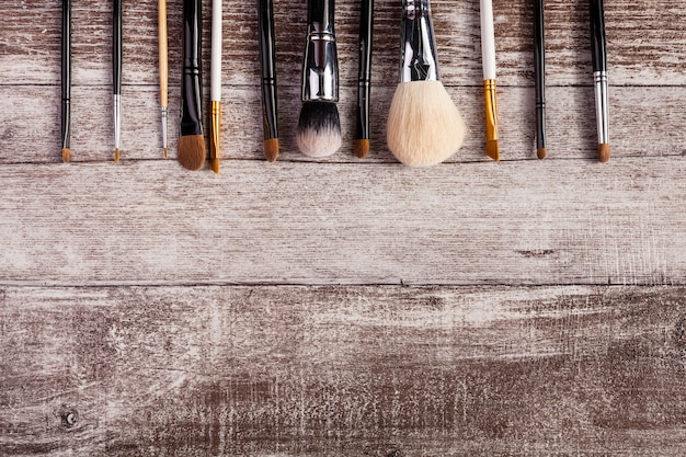 Make-up penselen in op bovenaanzicht afbeelding op houten achtergrond. cosmetische producten
