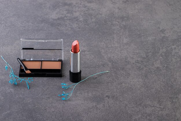 Make-up poeder in zwart rond plastic doosje met lippenstift en kwasten.