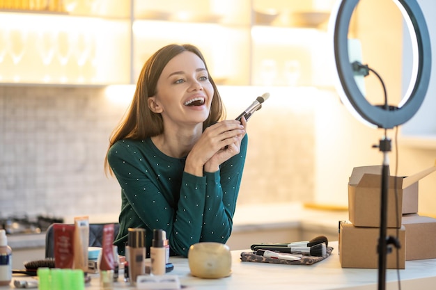 Make-up tips. Jonge lachende schoonheidsspecialiste die de geheimen van goede make-up uitlegt