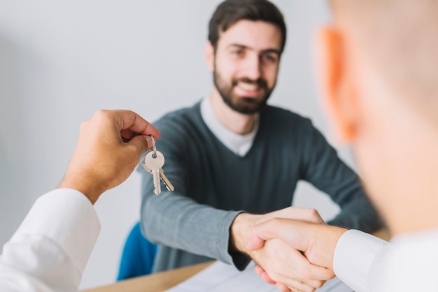 Makelaar in onroerend goed schuddende hand van cliënt en het houden van sleutels