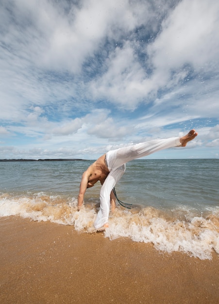 Gratis foto man aan het strand die alleen capoeira beoefent