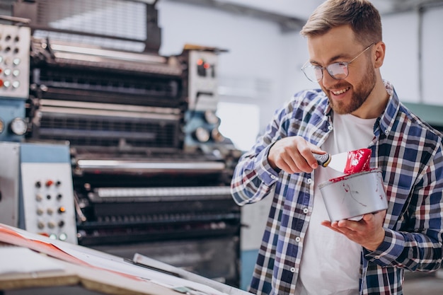 Man aan het werk in de drukkerij met papier en verf