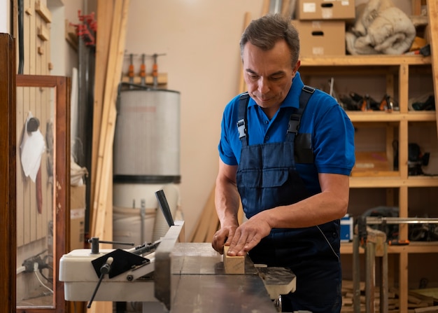 Gratis foto man aan het werk in zijn houtwinkel met gereedschap en uitrusting