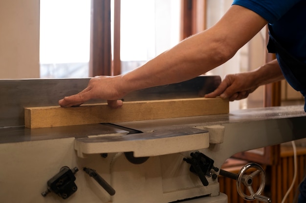 Gratis foto man aan het werk in zijn houtwinkel met gereedschap en uitrusting