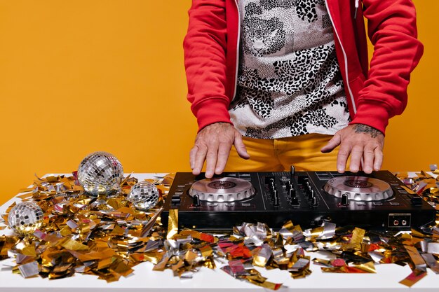 Man aan het werk met dj-controller op oranje muur