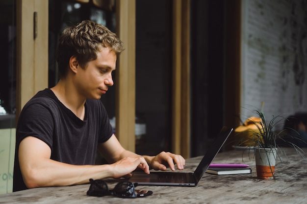 man aan het werk met een laptop in een café op een houten tafel