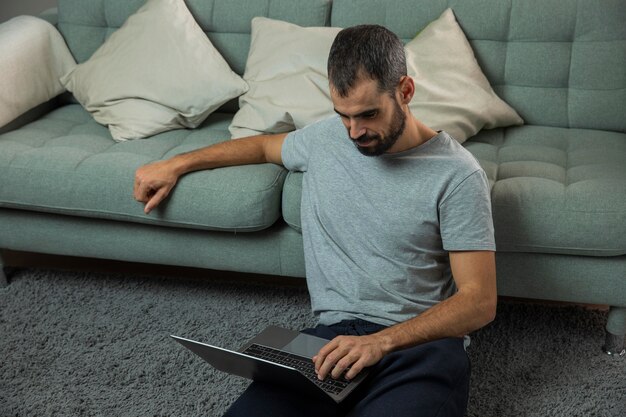 Man aan het werk op laptop naast bank