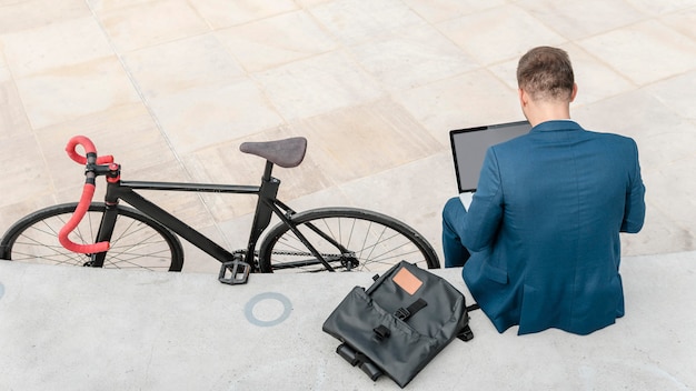 Gratis foto man aan het werk op laptop naast zijn fiets