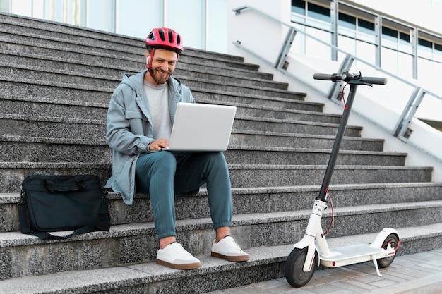 Man aan het werk op zijn laptop naast zijn scooter