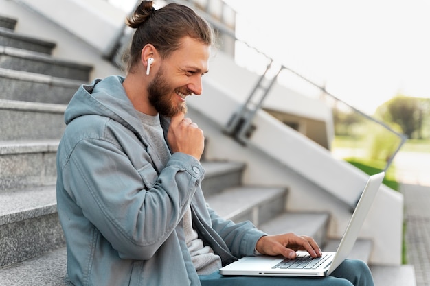 Gratis foto man aan het werk op zijn laptop naast zijn scooter