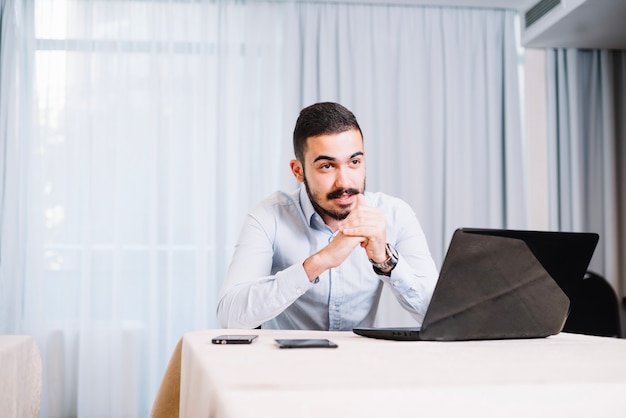 Man aan tafel met gadgets die vergadering hebben