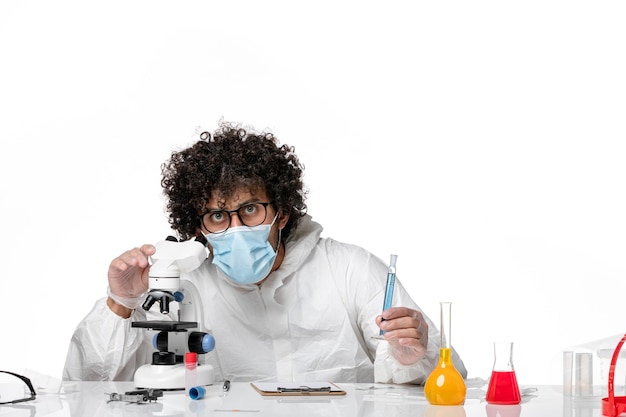 man arts in beschermend pak en masker met behulp van microscoop op wit