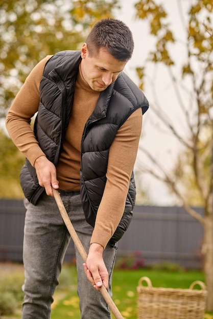 Man betrokken bij het schoonmaken van de tuin op herfstdag