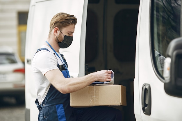 Man bij de vrachtwagen. Kerel in een leveringsuniform. Man in een medisch masker. Coronavirus concept.