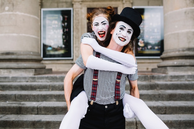 Man bootst het geven van piggyback rit aan vrouwelijke mime