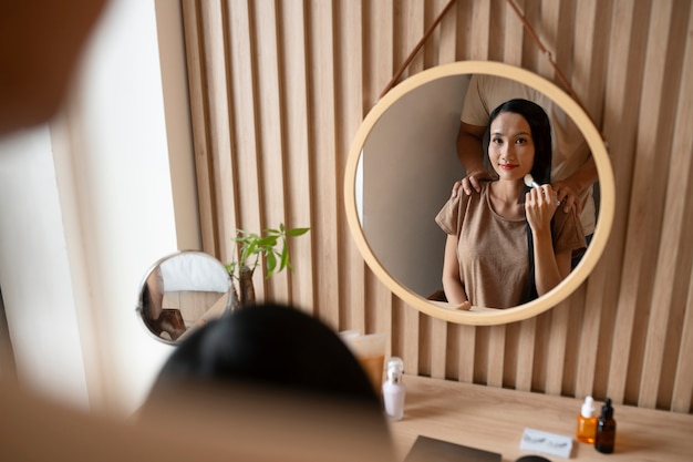 Man die aanhankelijk is met vrouw terwijl ze make-up opdoet en in de spiegel kijkt