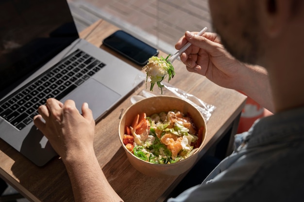 Man die afhaalmaaltijden eet en laptop gebruikt