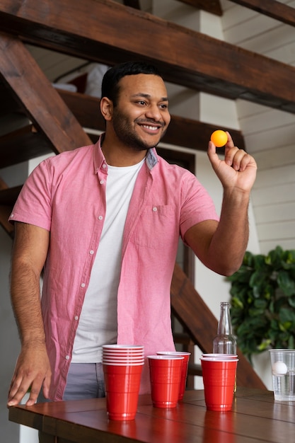 Man die bierpong speelt op een binnenfeestje