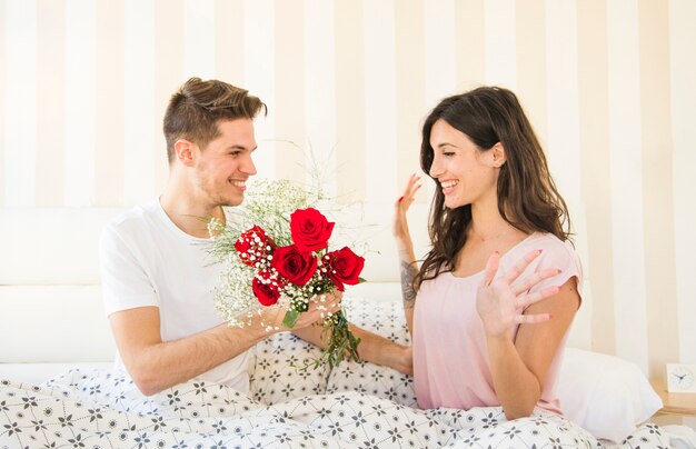 Man die bloemen geeft aan vrouw op bed