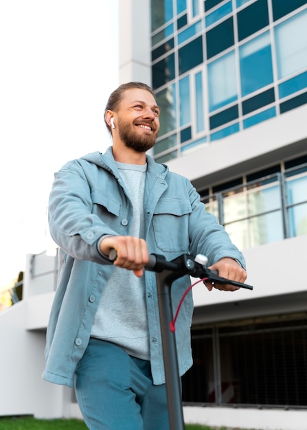 Gratis foto man die buiten op een milieuvriendelijke scooter rijdt